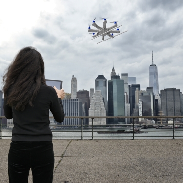 Young women using a drone over the East River in New York City. Young women using a drone over the East River in New York City.